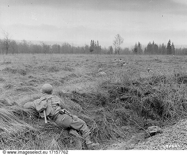 BELGIEN Sourbrodt -- 18. Dezember 1944 -- Männer der Kompanie M  des 3. Bataillons des 18. Infanterieregiments  der 1. Infanterie-Division  legen sich während eines großen deutschen Gegenangriffs  der später als Ardennenoffensive bekannt wurde  in Sourbrodt  Belgien  auf die Lauer nach deutschen Fallschirmjägern  die von anderen Männern des Regiments aus dem Wald getrieben werden -- Bild von Lightroom Photos / US Army *Bestmögliche Qualität. Nicht auf Staub oder Kratzer retuschiert.