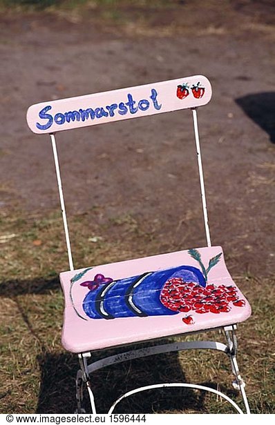 Bemalte Erdbeeren auf einem rosa Stuhl.