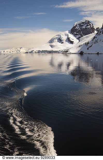 Berge und Schneelandschaft spiegeln sich im ruhigen Meerwasser im Südpolarmeer wider.