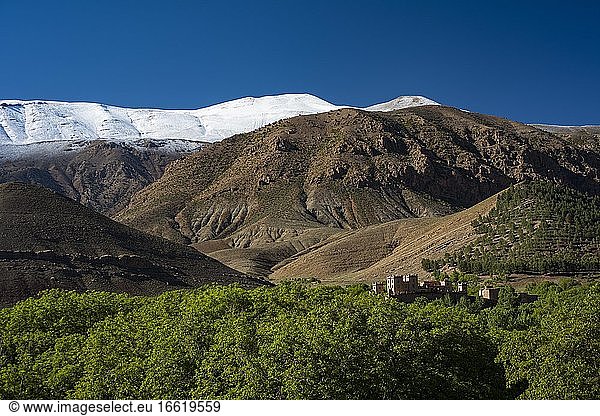 Berglandschaft mit schneebedecktem Berg  im Vordergrund Kasbah  Lehmburg der Berber  Tighremt  Ait Bouguemez-Tal  Tabant  Hoher Atlas  Marokko  Afrika
