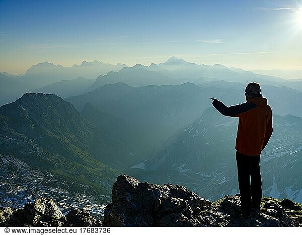Bergsteiger am Gipfel des Krn 2. 244m zeigt auf sein nächstes Ziel  Triglav-Nationalpark  Julische Alpen  Slowenien  Europa