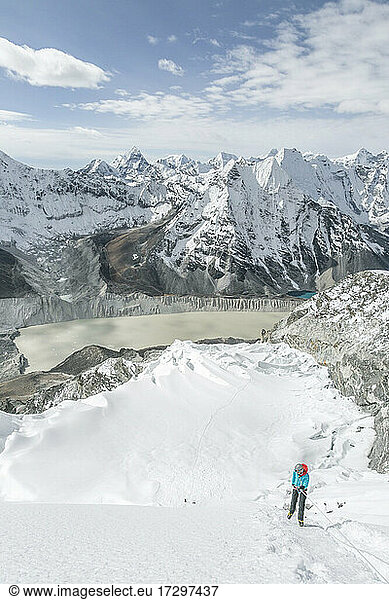 Bergsteiger in großer Berglandschaft mit blauem Himmel und Gletschersee
