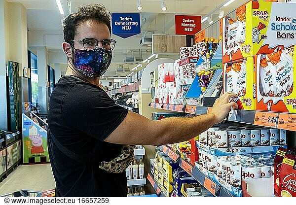Berlin  Deutschland. Älterer schwuler Mann  der in einem örtlichen Supermarkt Lebensmittel einkauft und aufgrund des Corona-Ausbruchs und der Covid-19-Krise einen schützenden Mundschutz trägt. In Deutschland ist das Tragen von Gesichtsmasken in allen geschlossenen  öffentlichen Räumen Pflicht.