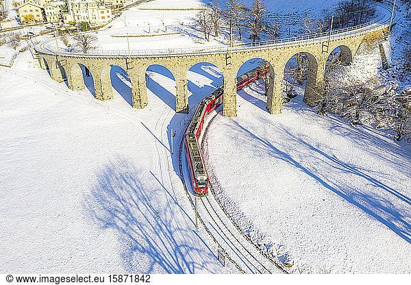 Bernina Express passes under the helical (spiral) viaduct of Brusio  UNESCO World Heritage Site  Valposchiavo  Canton of Graubunden  Switzerland  Europe