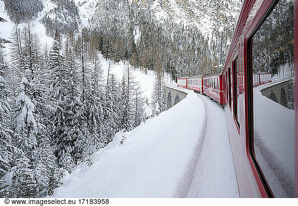 Bernina Express train in the alpine landscape covered with snow  Preda Bergun  Albula Valley  Graubunden Canton  Switzerland  Europe