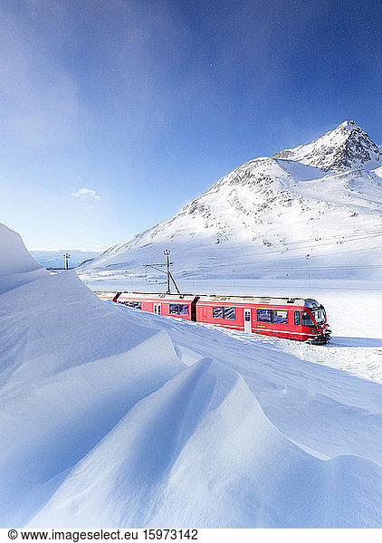 Bernina Express transit along Lago Bianco during winter blizzard  Bernina Pass  Engadine  Graubunden canton  Switzerland  Europe