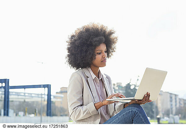 Berufstätige Frau benutzt Laptop im Freien
