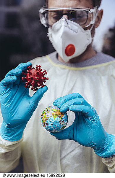 Beschäftigte im Gesundheitswesen halten ein Modell des Coronavirus und einen Mini-Globus