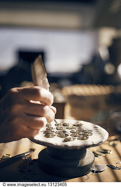 Beschnittenes Bild einer Goldschmiedin  die in einer Werkstatt Schmuck herstellt