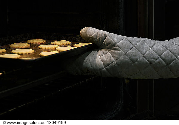 Beschnittenes Bild einer Person  die ein Blech mit gebackenen Keksen entfernt