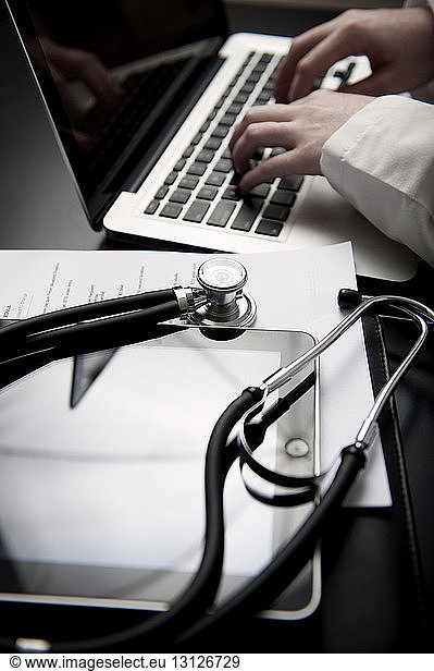 Beschnittenes Bild eines Arztes mit Laptop mittels Stethoskop