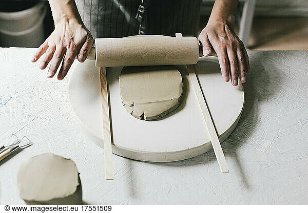 Besitzerin rollt Ton am Tisch in einem Keramikgeschäft