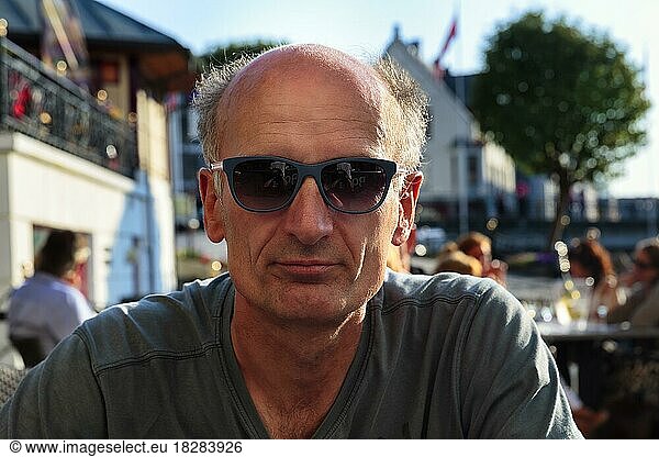Best Ager  Portrait mit Sonnenbrille  leger  unrasiert  sitzt im Biergarten  Norwegen  Europa