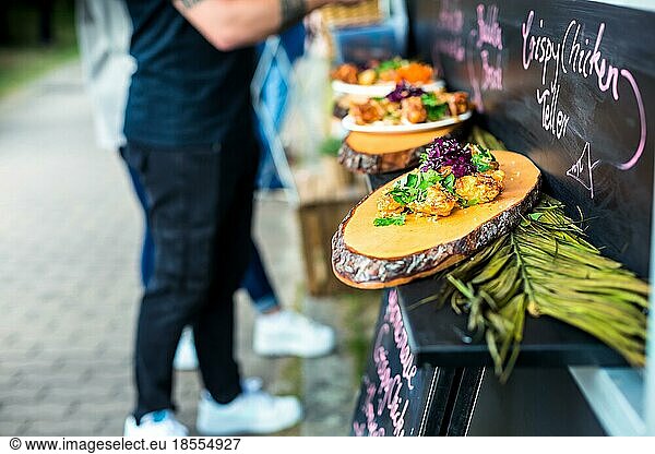 Bestellung von Street Food am Food Truck. Pikante Hähnchenflügel mit Gemüse und Kräutern