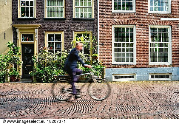 Bewegung unscharf Fahrradfahrer Radfahrer Mann auf Fahrrad sehr beliebtes Transportmittel in den Niederlanden in Straße mit alten Häusern von Delft  Niederlande  Europa