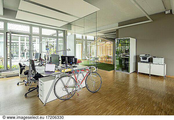 Bicycle  laptop and computers at desk in open plan office