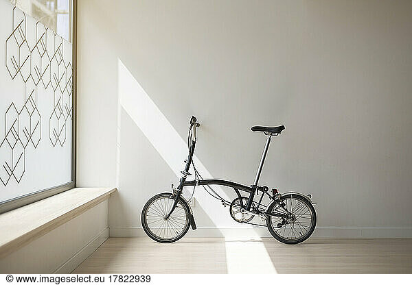 Bicycle leaning on white wall in yoga studio