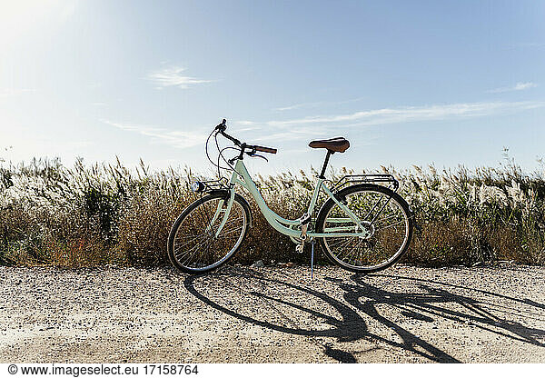 Bicycle parked near rice field against sky at Ebro's Delta on sunny day  Spain