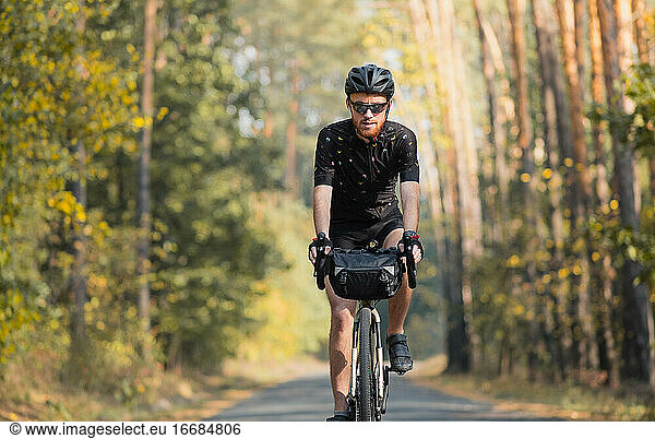 Bicycle tourism: man rides a touring bike through the forest. Bi
