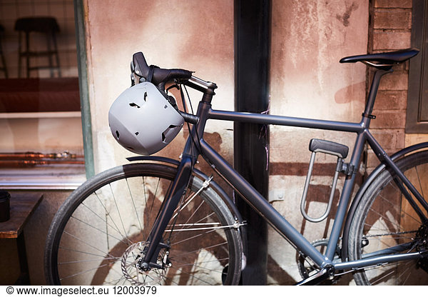 Bicycle with helmet parked against wall at city