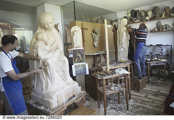 Bildhauer meißeln Figuren aus Holz