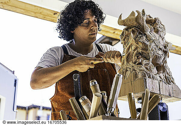 Bildhauerin schnitzt Holzfigur in der Arbeit
