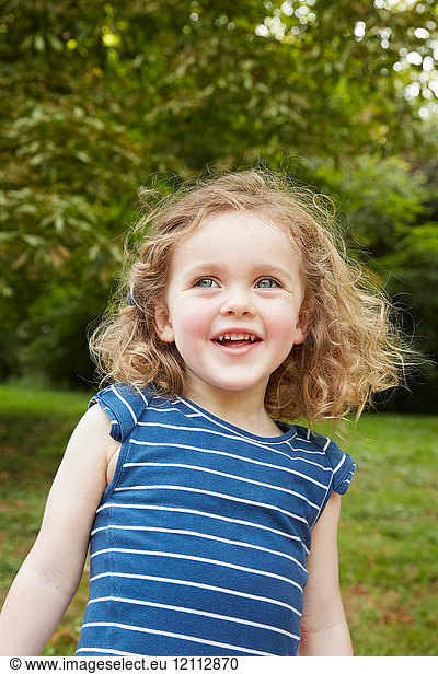 Bildnis eines blonden  gewellten Mädchens mit blauen Augen im Park