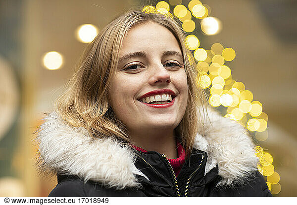 Bindung junge Frau lächelnd gegen Weihnachtsbeleuchtung während der Feiertage