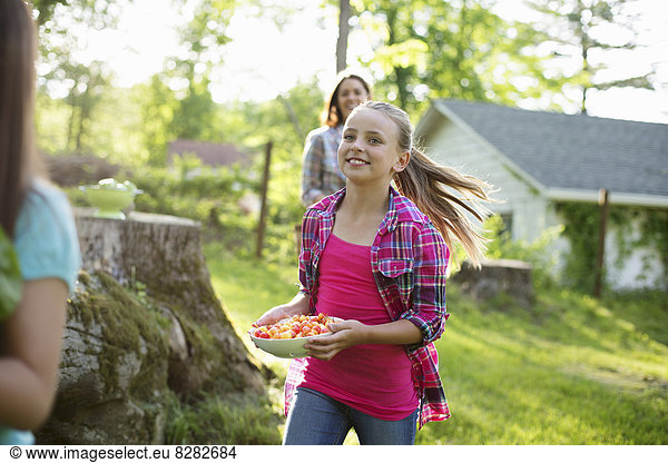 Biologische Landwirtschaft. Sommerfest. Drei Mädchen rennen über das Gras.