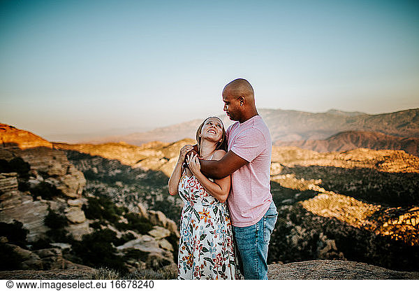 Biracial Couple hugging and looking at each other on a mountain top