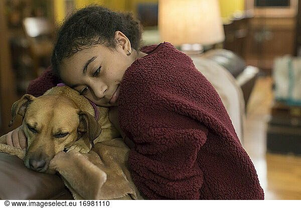 Biracial eleven year-old girl embracing a small brown dog