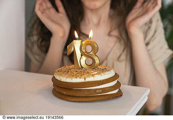 Birthday cake with lit number 18 candle at home