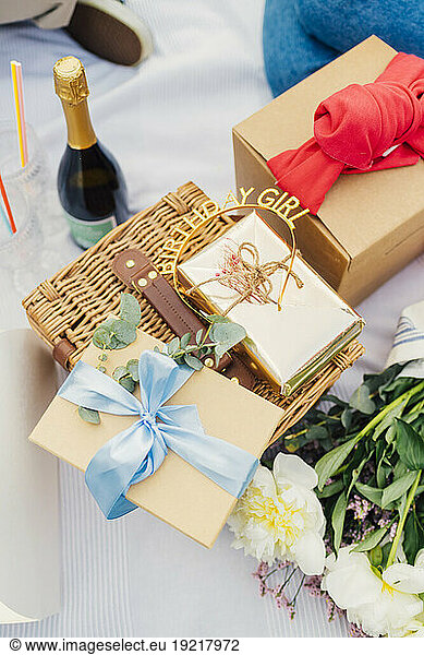 Birthday gift boxes on picnic basket with wine bottle and bouquet of flowers