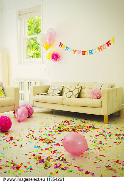 Birthday sign balloons and confetti in living room