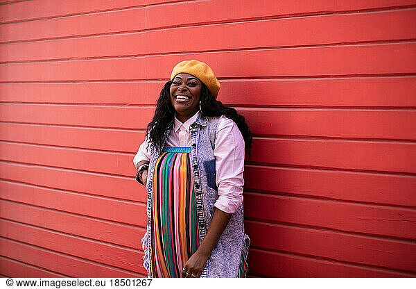 Black Adult Woman Laughing Towards Camera with Red Wall