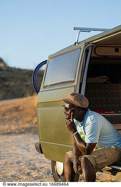 black african american man sitting in his camper van thoughtfully