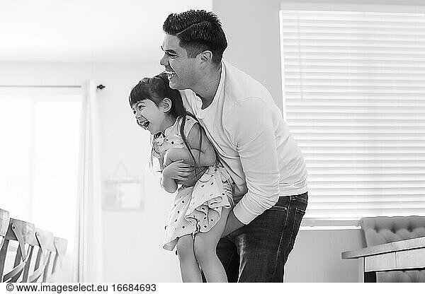 Black and white photo of dad holding daughter  both laughing.