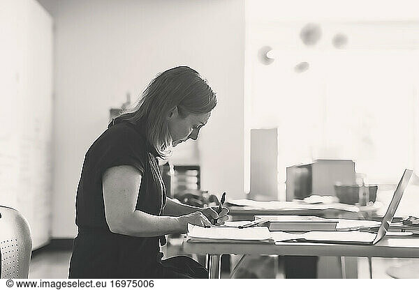 Black and white photo of teacher taking notes on her desk.