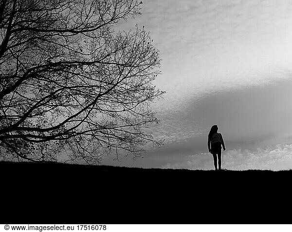 black and white silhouette of girl with tree against sky