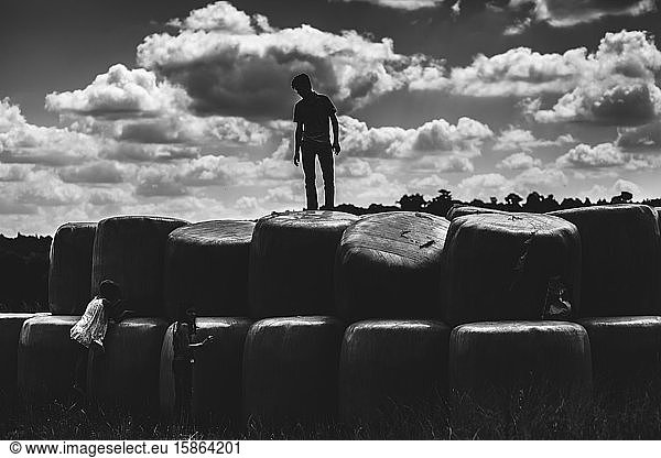 Black and White Silhouette of Teen Boy and Kids by Hay Bales