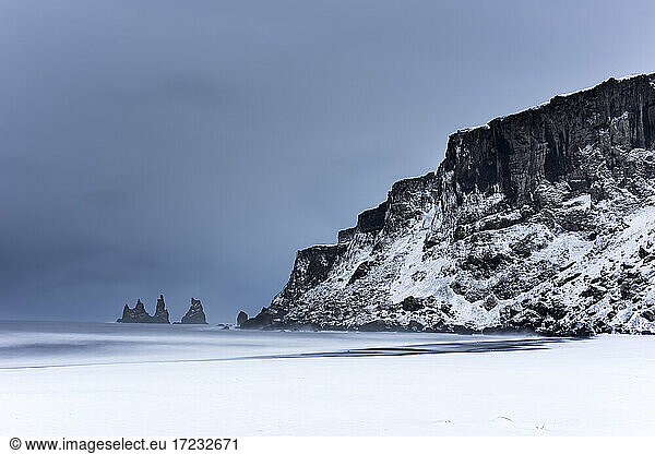 Black basalt sea stacks and snow covered black sand beach  Vik  Iceland  Polar Regions