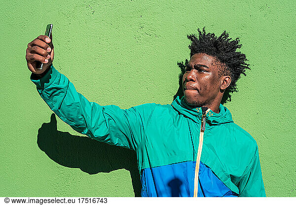 Black boy taking a selfie with his mobile phone.
