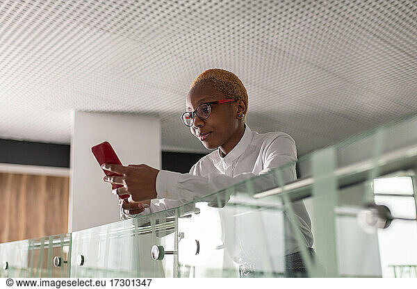 Black businesswoman browsing cellphone near railing