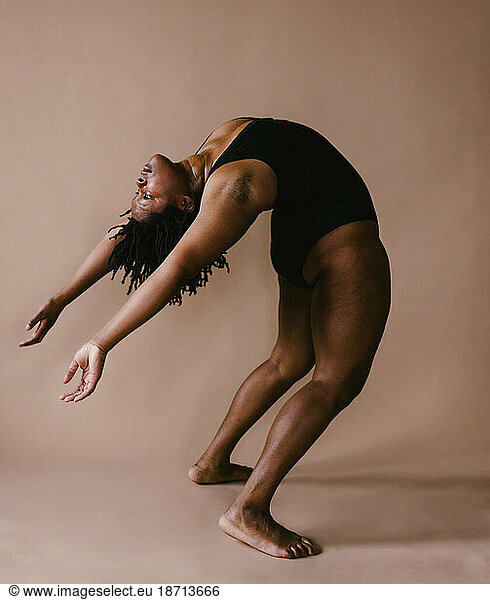 Black female dancer leans back to backbend in dance pose