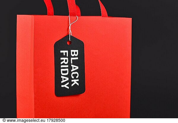 Black Friday sale label on red paper shopping bag on black background