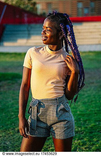 black girl with purple braids posing in a park