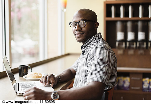 Black man using laptop in coffee shop