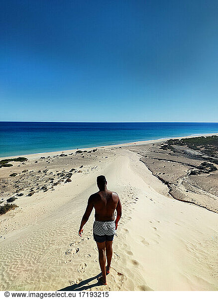 Black man walking down a dune on sotavento beach  Fuerteventura
