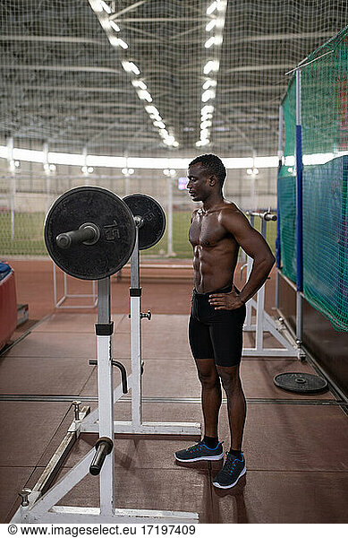 Black sportsman preparing to exercise with barbell