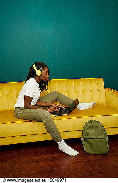 Black styled student sitting on a sofa with a computer